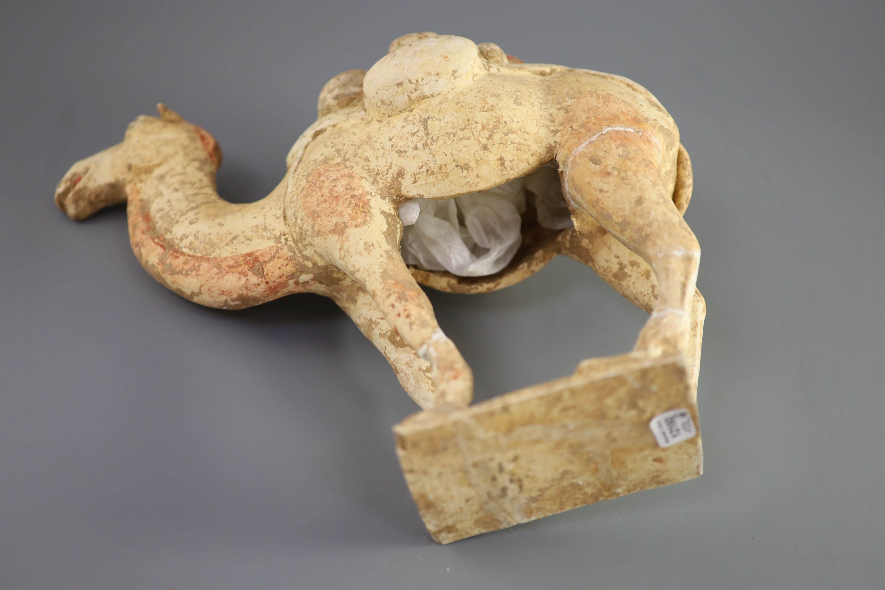 A Chinese pottery model of a Bactrian camel and a similar head of a man, Tang Dynasty, 28 cm and 16.5 cm high including bases